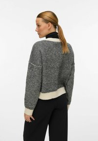 Maglione lavorato a maglia in un motivo pied de poule bianco e nero con orlo color crema. Presenta una vestibilità rilassata e spalle larghe e scese.