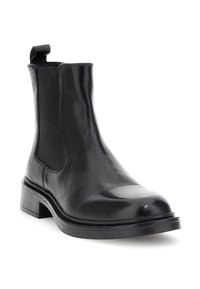 Botín Chelsea de cuero negro hasta el tobillo con panel lateral elástico, lengüeta en la parte trasera y tacón bajo apilado sobre fondo blanco.