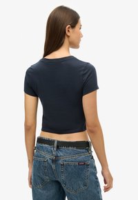 Marineblauw cropped t-shirt van zacht materiaal, met korte mouwen en een ronde halslijn, gecombineerd met een high-waist spijkerbroek.