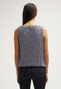 Ärm-lös topp i marinblått och vitt mönster, med en texturerad diamantdesign, nyckelhål på baksidan och mjukt tyg.