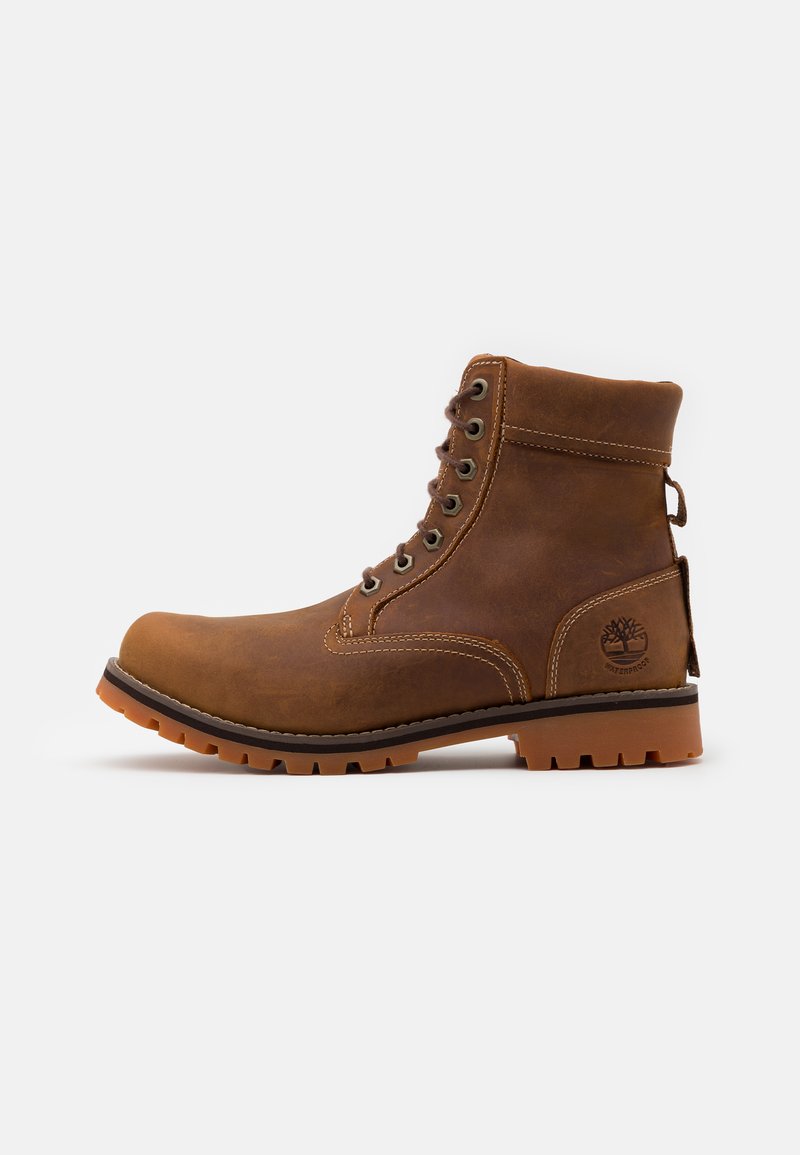 Stivale in pelle marrone con colletto imbottito, occhielli in metallo e suola in gomma. Presenta un design impermeabile e logo impresso sul tallone.