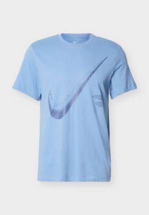 Svijetloplava majica kratkih rukava s velikim teksturiranim Nike Swoosh logotipom preko prsa i malim tiskanim tekstom ispod logotipa na desnoj strani.