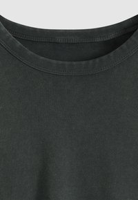 Σκούρο πράσινο, κοντομάνικο μπλουζάκι με ριμπ λαιμόκοψη. Ομαλή υφή με ομοιόμορφα ραφές. Χωρίς ορατά σχέδια ή γραφικά.