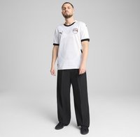 Biely športový dres s krátkym rukávom, čiernymi akcentmi a geometrickým vzorom, v kombinácii s čiernymi širokými nohavicami a čiernymi topánkami.