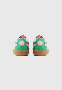 Et par grønne og rosa suede Puma sneakers med gummisåler vist fra baksiden på en enkel hvit bakgrunn.