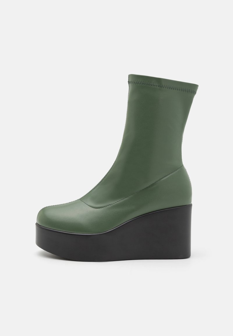 Green synthetic ankle boot with a smooth texture, rounded toe, and a high black platform sole. Seam detailing along the top edge.