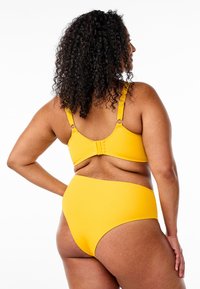 Gul bikini-set med justerbara band och spänne. Slät tygkvalitet med hög midja och minimala sömnadsdetaljer.