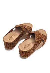 Brown leopard print wedge sandals with a cross strap design, made of suede, featuring a cork heel and a soft insole with branding.