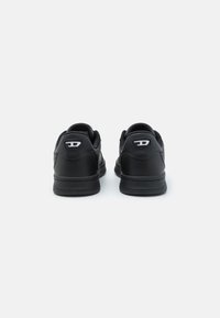 Sapatilhas de couro negras com um design de perfil baixo, parte traseira texturizada e acentos em branco no logotipo. Apresentam uma sola almofadada para conforto.