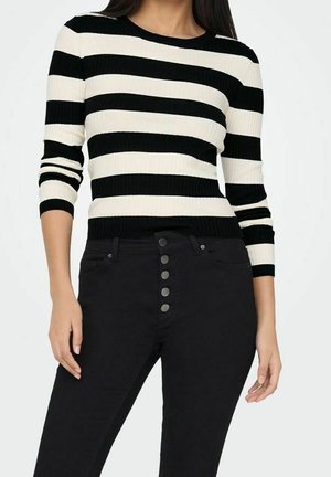 Svartvit randig ribbstickad tröja med rund halsringning och långa ärmar, kombinerad med svart högmidjade jeans med knappdetaljer.