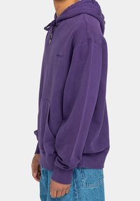 Sudadera morada con un bolsillo tipo canguro, capucha con cordón y puños acanalados. Hecha de una tela suave, con un logo sutil en el pecho.