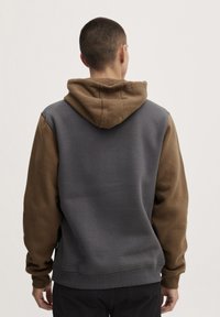 Hoodie met een twee-kleurig ontwerp; grijze body en bruine mouwen. Zachte textuur, geribbelde manchetten en een kangoeroezak.