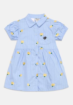 Lichtblauwe jurk met korte mouwen, knopen aan de voorkant, kleine kraag, gele fruitborduursels en een zak met een zwart hartvormig label.