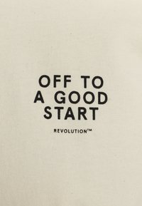 Off-white katoenen stof met vetgedrukt zwarte tekst: "OFF TO A GOOD START" boven "REVOLUTION™", met een glad, onbewerkt oppervlak.