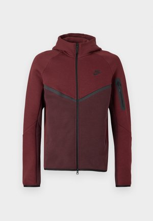 Bordo zip-up dukserica s kapuljačom, s crnim detaljima i bočnim džepom na zip. Izrađena od mekog, teksturiranog materijala s dizajnom u boji.
