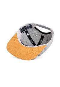 Casquette grise avec une visière en daim beige, présentant un intérieur texturé et une sangle noire. Les étiquettes internes indiquent les détails de la marque et du modèle.