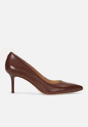 Brun læder pumps med spids tå og mellemhøj stilethæl på en hvid baggrund.
