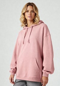 Felpa rosa in morbido cotone, con tasca frontale, cappuccio con cordino e polsini a costine. Vestibilità comoda con una consistenza liscia.