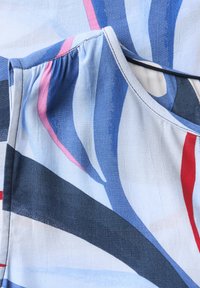 Tejido fluido con un patrón abstracto en azul, rosa y rojo. Presenta un suave brillo, con un escote gathered y una textura suave.