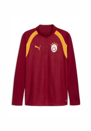Sudadera deportiva burdeos de manga larga con detalles amarillos en los hombros, cremallera al cuarto, logo de Puma y emblema del club de fútbol Galatasaray con estrellas en el pecho.