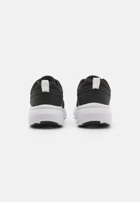 Schwarze Sportschuhe mit Mesh-Obermaterial, kontrastierender weißer Zwischensohle und strukturiertem schwarzen Außensohlen. Verfügt über eine Zuglasche an der Ferse.