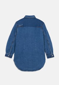 Camicia di jeans in due tonalità di blu con colletto, maniche lunghe e polsini con bottoni. Presenta un sottile ricamo sulla spalla.