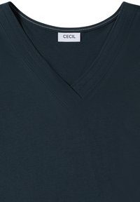T-shirt col en V bleu sarcelle foncé avec coutures doubles apparentes autour du col et une étiquette de marque blanche indiquant "CECIL".
