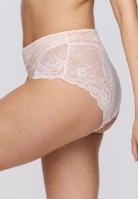 Culotte alte in pizzo di colore rosa chiaro, con motivi floreali, bordi scallopati e tessuto trasparente per un aspetto delicato.