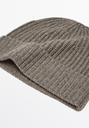 Berretto lavorato a maglia grigio con una texture a coste. Il tessuto appare spesso e caldo, presentando un risvolto nella parte inferiore per un ulteriore effetto di profondità.