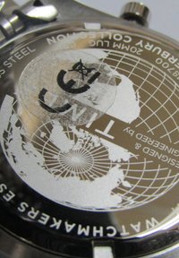 Fond de montre en acier inoxydable avec un design de carte du monde, de forme circulaire, et du texte gravé incluant "20M" et le logo de la marque.