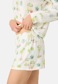 Vitt, kort pyjamasset med en färgglad design av cocktaildrinkar, limefrukter och kaktusar. Mjukt, lätt tyg med elastisk midja.