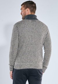 Strickpullover mit hohem Kragen, der ein Hahnentrittmuster in Grau und Creme aufweist, mit gerippten Bündchen und Saum, aus strukturiertem Stoff gefertigt.