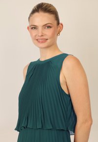 Teal geplooid top met een gelaagd ontwerp. Lichtgewicht stof, zonder mouwen, met een ronde halslijn en zachte plooien over het geheel.