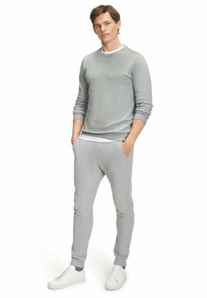 Grauer Sweatshirt und passende Jogginghose aus weichem Stoff. Das Outfit hat einen Rundhalsausschnitt und elastische Bündchen, kombiniert mit weißen Sneakers.