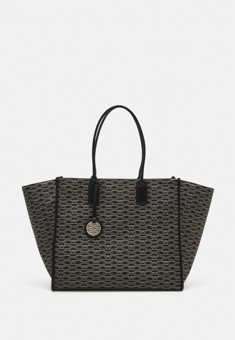 Sac fourre-tout à motifs noir et beige avec un large dessus ouvert, deux poignées noires, et une étiquette de logo ronde. Présente une forme structurée et un matériau texturé.