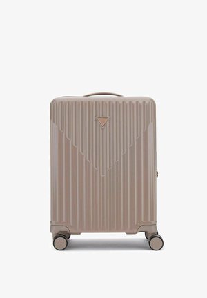 Valise rigide beige avec des rainures verticales, logo triangulaire de la marque, poignée supérieure et quatre roulettes pivotantes.