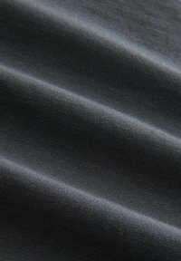 Sort stof med en glat, men tekstureret overflade, der har fine ribber og bløde folder, hvilket indikerer et let, alsidigt materiale.