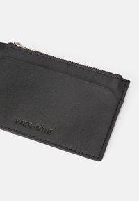 Musta nahkainen lompakko-korttikotelo, jossa on sileä pinta, vetoketjukiinnitys ja kohokuvioitu "PIER•ONE" -logo.