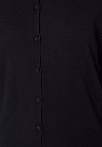 Schwarzer Strickcardigan mit durchgehender Knopfleiste. Er verfügt über sechs schwarze Knöpfe auf einem strukturierten Stoff und hat ein schlichtes, figurbetontes Design.