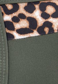 Zeleni materijal s glatkom teksturom ima leopardov uzorak u smeđoj i crnoj boji, smješten unutar kontrastne crne ploče.