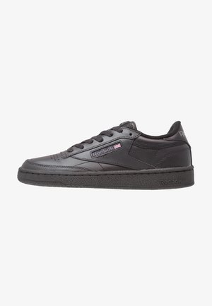 Baskets basses noires Reebok avec laçage à l'avant, semelle texturée et petit logo Union Jack sur le panneau latéral.