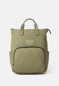 Olivovozelená taška s dvoma hornými uchami, hlavný kompartmán na zips, predná kapsa s čiernym lemovaním a logom "Calvin Klein Jeans".