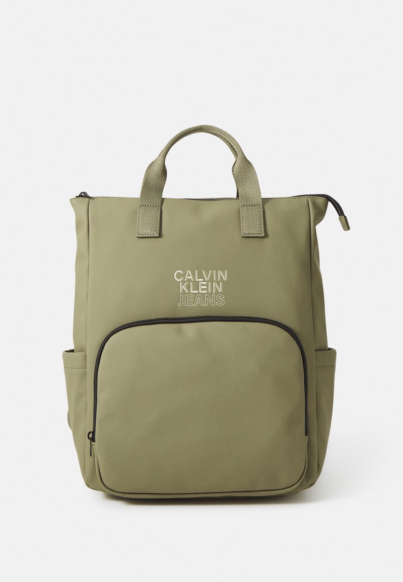 Olivovozelená taška s dvoma hornými uchami, hlavný kompartmán na zips, predná kapsa s čiernym lemovaním a logom "Calvin Klein Jeans".