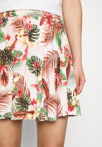 Jupe à motifs floraux en tissu léger. Présente des feuilles tropicales et des fleurs vibrantes dans des tons verts, roses et jaunes. Taille élastique.