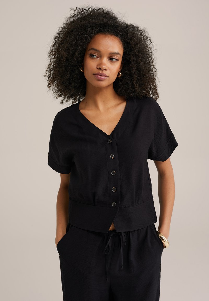 Must värvi lühikeste varrukatega tops, millel on V-kaelus, nööpidega avatud esiosa, tekstuurne kangas ja lühike alläär.