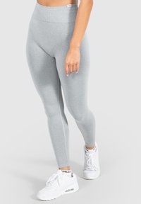 Grijze leggings van rekbare stof, met een hoge tailleband. Draag ze met witte sport sneakers, die een schoon design hebben.