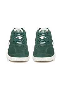Zielone zamszowe trampki z białymi elementami, okrągłymi sznurowadłami, wyściełanym kołnierzem i logo na języku. Okrągły nosek i teksturowana podeszwa zapewniająca przyczepność.