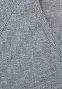Tessuto grigio a coste con design a scollo a V. La texture è leggermente ruvida e le cuciture sono visibili lungo i bordi.