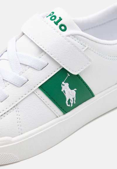 Fehér bőr sneaker, zöld oldalsó panele fehér hímzett logóval. Fűzők és tépőzáras szíj a záródáshoz.