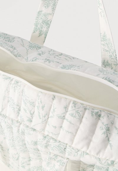 Õmmeldud kangast õlakott kahvatu rohelise botaanilise mustriga, avatud tõmblukuga ülalt ja sobivate mustriliste sangadega valgel taustal.